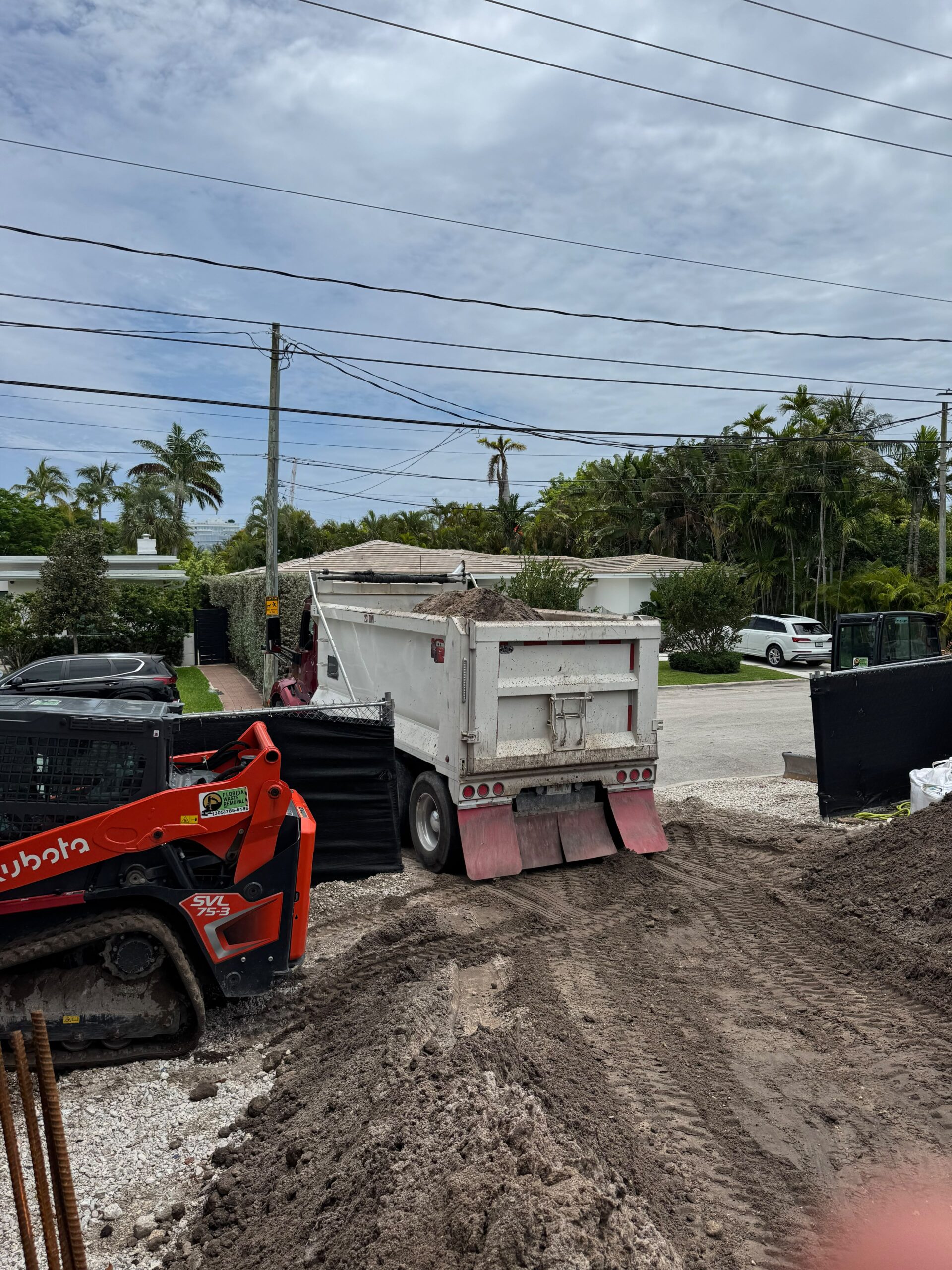 Dump truck and Kubota loader moving dirt on a residential site